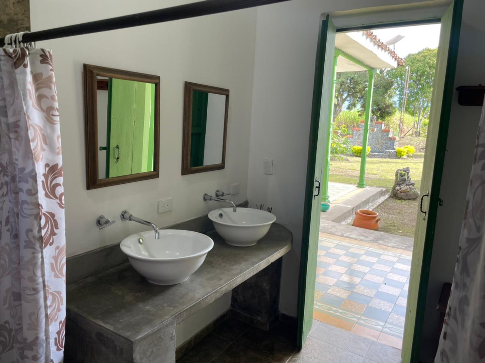 A bathroom with twin vessel sinks opening onto the garden and porch